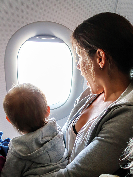 A child and mother look through the window on an airplane.