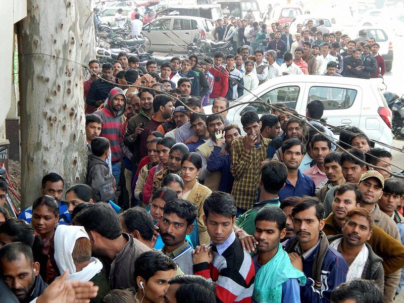 People wait in long queues outside an ATM