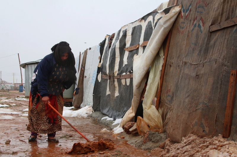 A Syrian refugee shovels mud _092