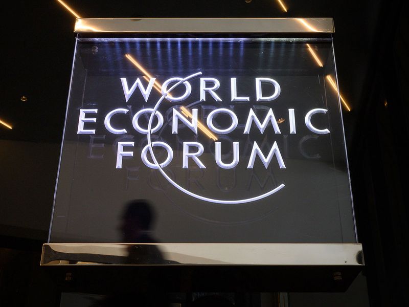 A man walks past a sign of the World Economic Forum