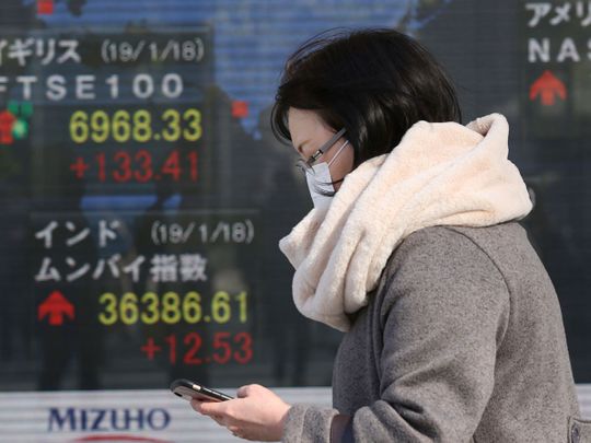 A woman walks by an electronic stock board of a securities firm in Tokyo
