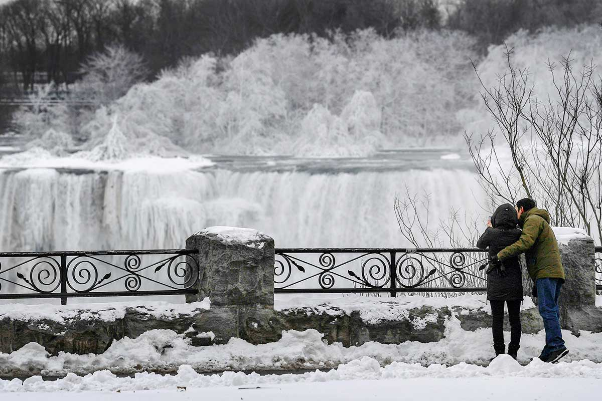 A couple takes a photo of ice formed on the American Falls in Niagara Falls