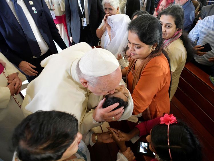 Pope Francis kisses a child during a visit