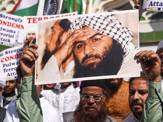 Protesters hold a scratched photo of Jaish-e-Mohammad group chief