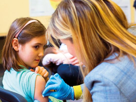 A 9-year-old rolls up her sleeve for a vaccination at a clinic in Portland