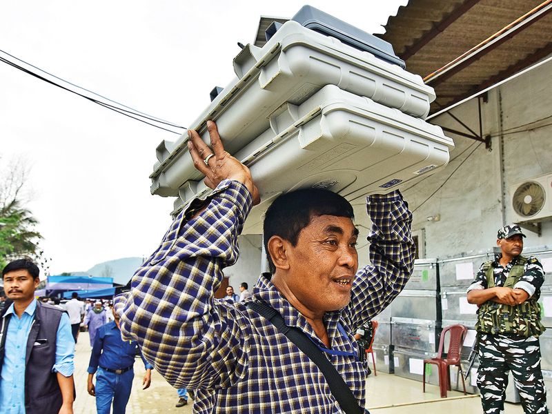 A polling officer carries electronic voting machines