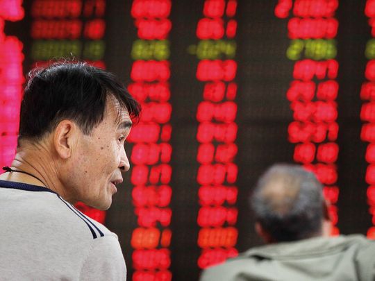 Investors monitor stock prices at a brokerage house in Beijing