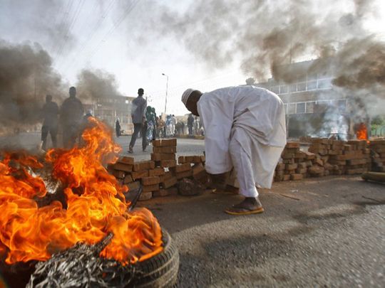 Sudanese protesters block a street with burning tires