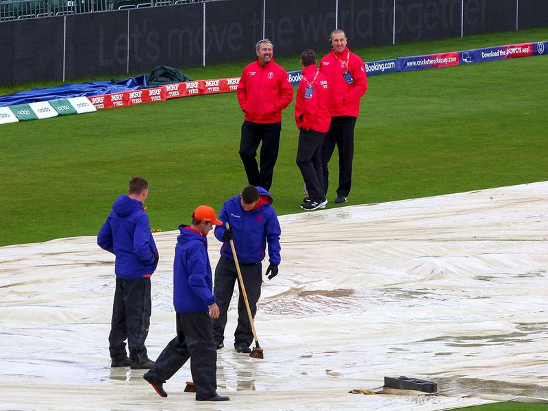 Umpires inspect the pitch