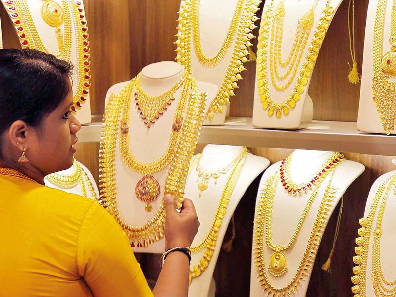 A saleswoman selects gold necklaces in a jewellery showroom in India