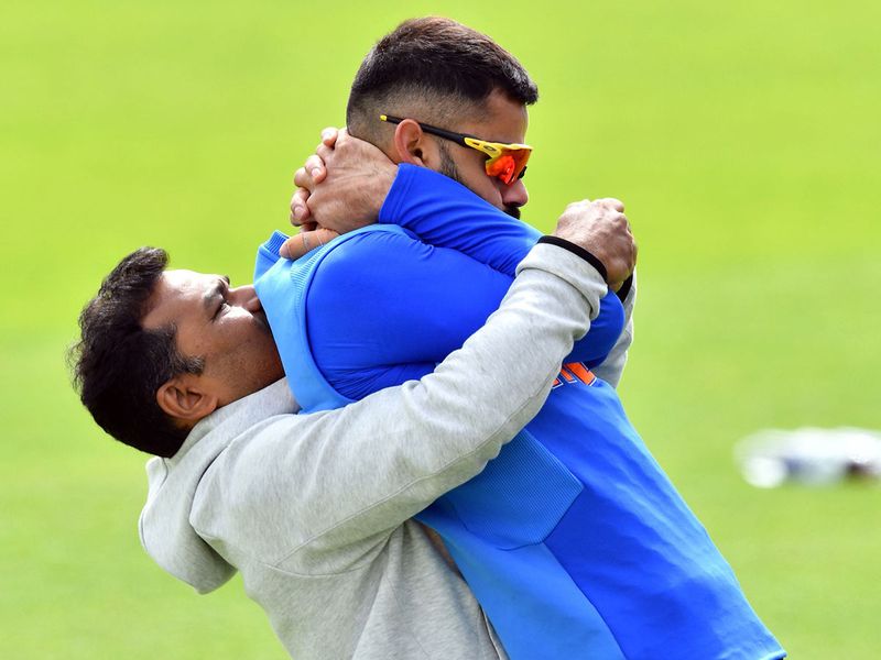 A trainer assists Virat Kohli to stretch