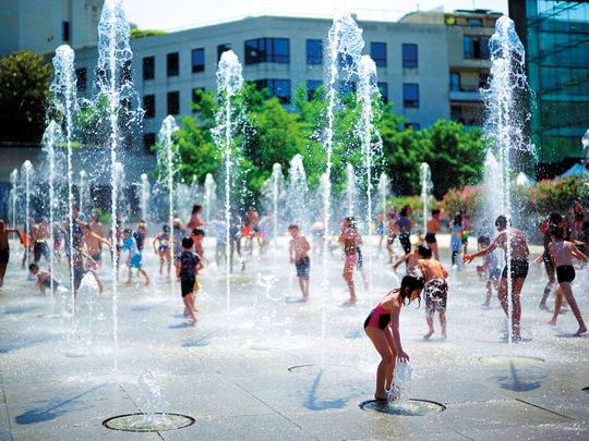 Children play at a fountain in a park