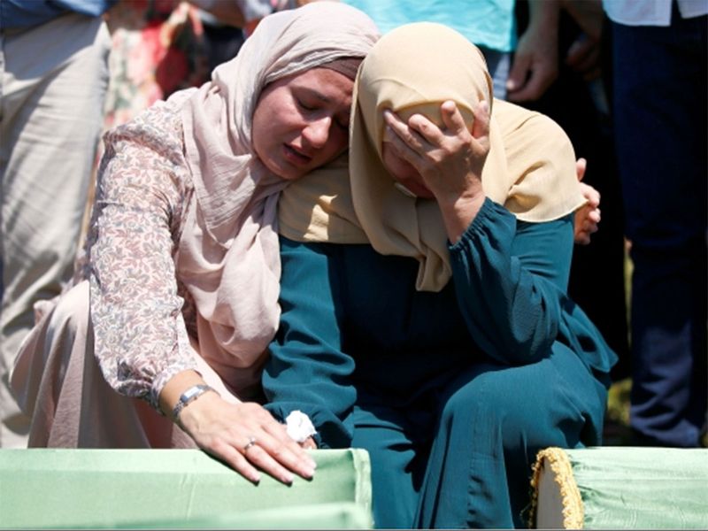 Bosnian Muslim women cry near the coffins during a mass funeral 23121