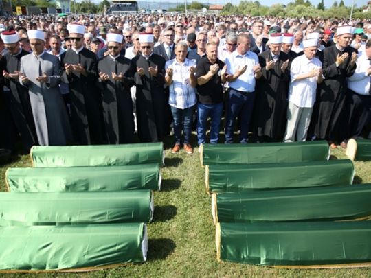Bosnian Muslims pray in front of coffins during a mass funeral in the village of Hambarine, near Prijedor, Bosnia and Herzegovina. -091