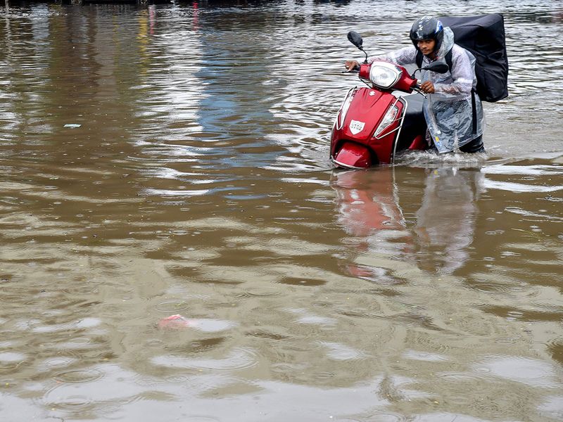 A deliveryman pushes his vehicle on a flooded road