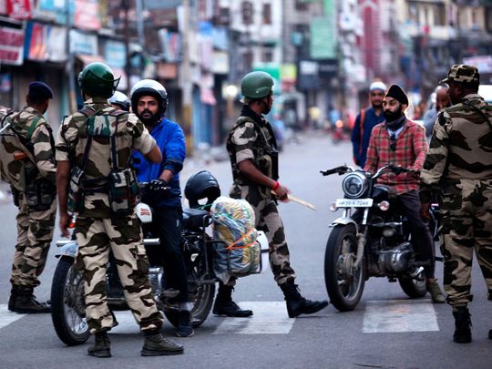 Security personnel question motorists on a street in Jammu