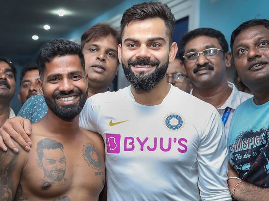 Virat Kohli poses for a photograph with his fan 