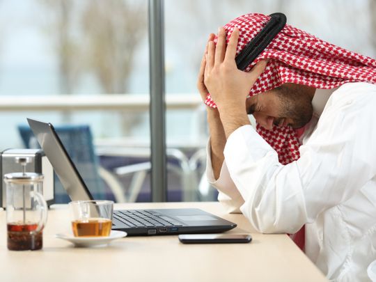 Arab man in front of laptop upset at his bank