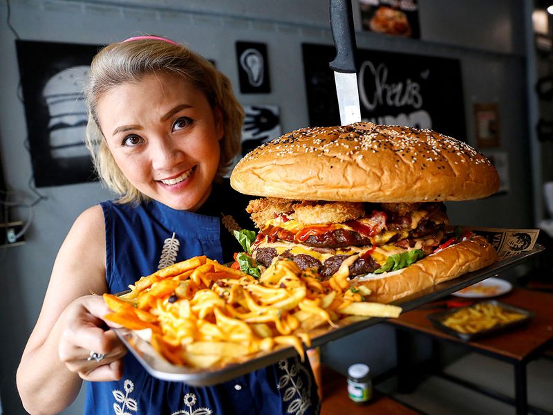 A woman holds up what the Chris Steaks & Burgers restaurant says is Thailand's biggest burger weighing more than 6 kilograms, before a competition held to eat it at the restaurant in Bangkok, Thailand.