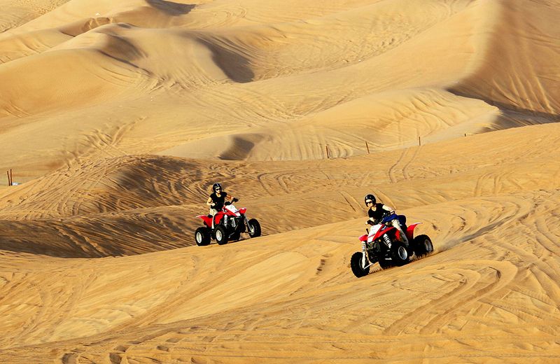 Tourists ride in the sand dunes in the desert along Hatta road