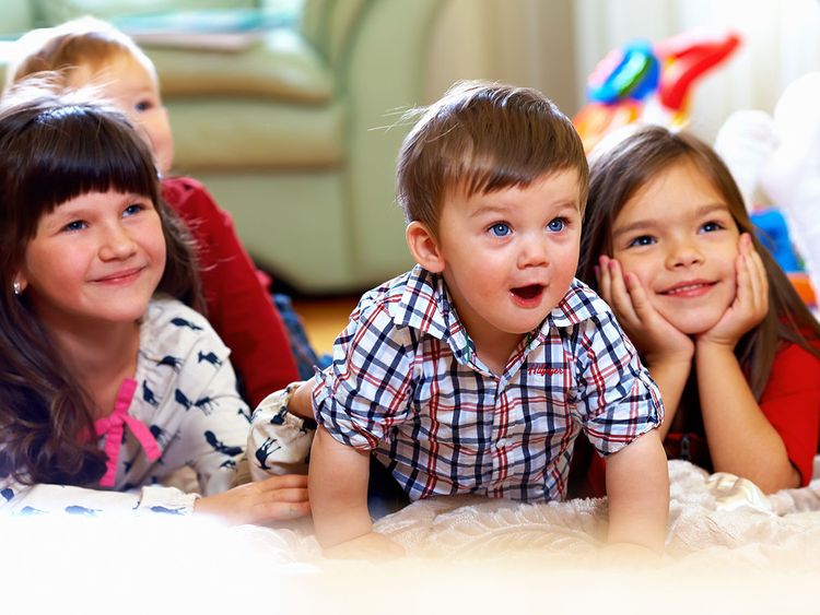 group of happy kids watching tv at home