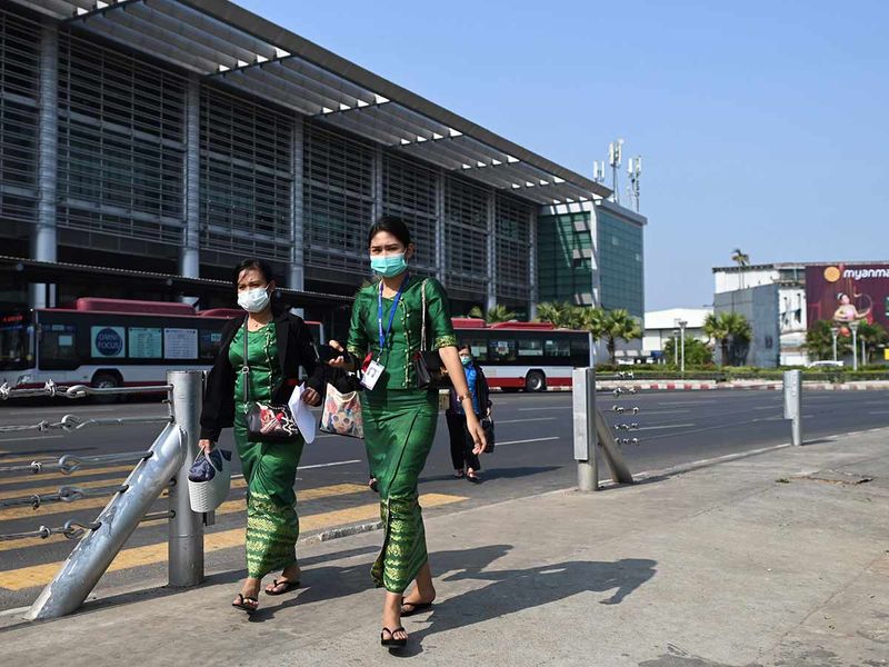 People wear protective facemasks outside the Yangon international aiport in Yangon on January 31, 2020. 