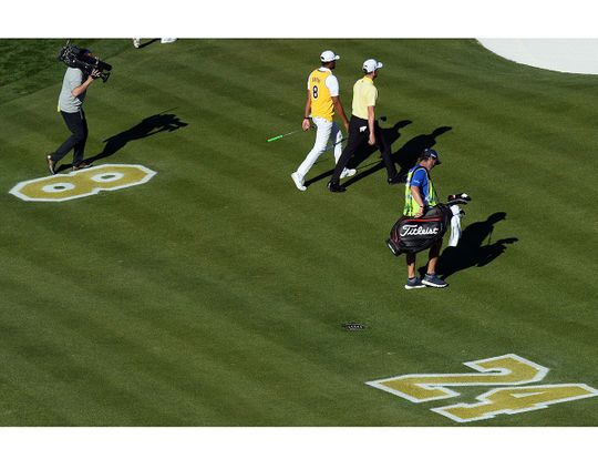  Tony Finau wears the jersey of Kobe Bryant while walking alongside Webb Simpson past a memorial on the fairway of the 16th during the final round of the Waste Management Phoenix Open golf tournament at TPC Scottsdale.