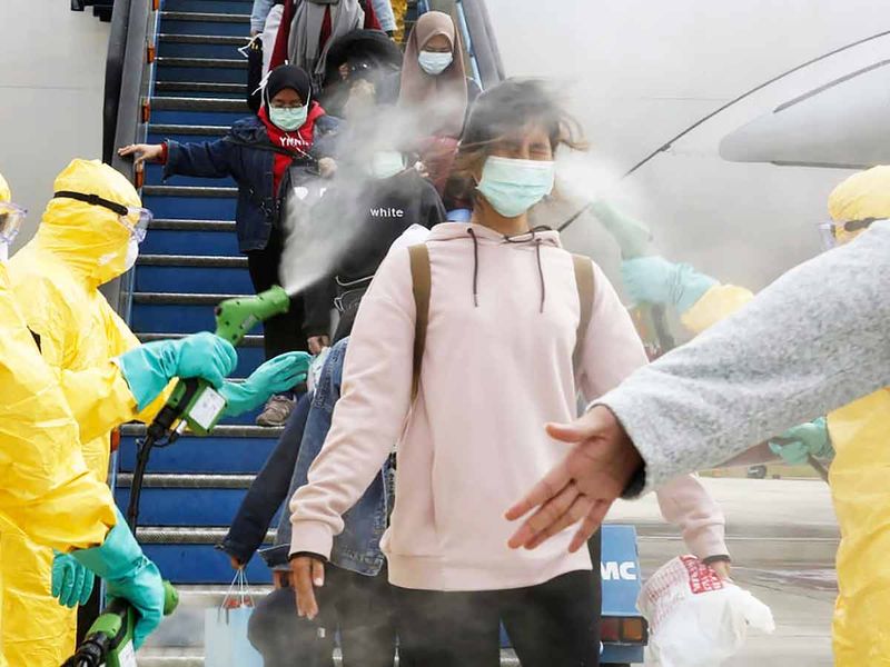 Indonesians who arrived from Wuhan, China, are sprayed with antiseptic at Hang Nadim Airport in Batam, Indonesia. 