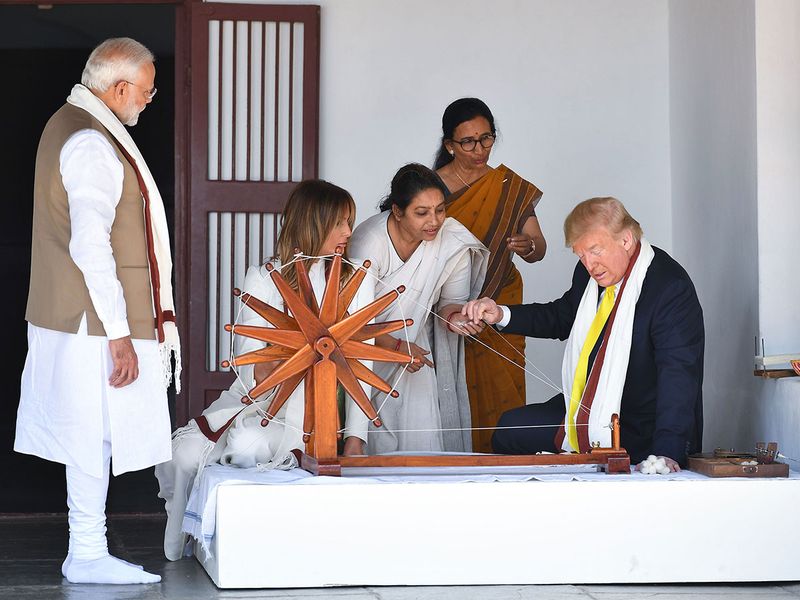 Donald Trump holds a string while checking a charkha, or spinning wheel, as Melania Trump (2L) and Narendra Modi (L) look on during their visit at the Gandhi Ashram in Ahmedabad on February 24, 2020. 