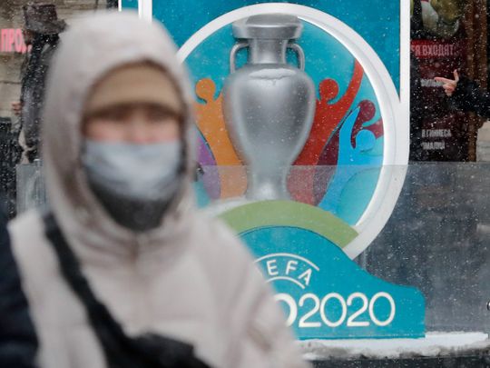 FILE PHOTO: A person wearing a protective face mask walks past the Euro 2020 countdown clock in central Saint Petersburg, Russia March 1, 2020. REUTERS/Anton Vaganov/File Photo
