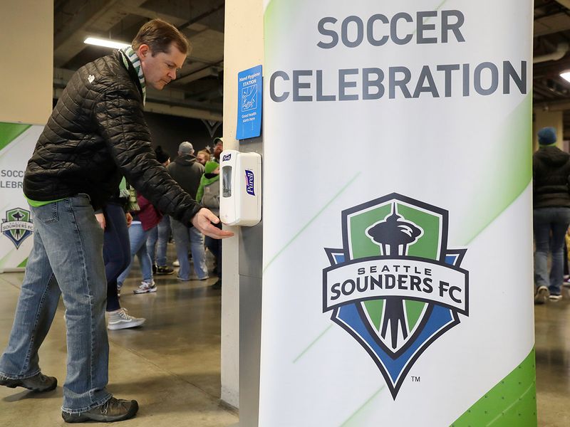 A man makes use of a hand-sanitizing station at CenturyLink Field prior to an MLS soccer match between the Seattle Sounders and the Chicago Fire, Sunday, March 1, 2020, in Seattle. Major North American professional sports leagues are talking to health officials and informing teams about the coronavirus outbreak. (AP Photo/Ted S. Warren)