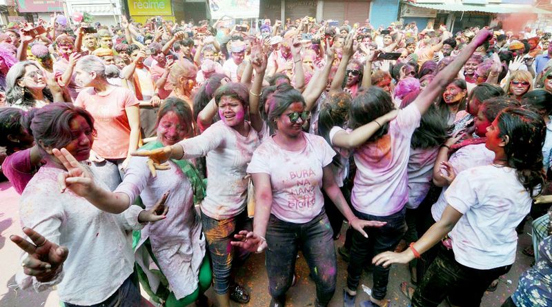 People daubed in colours cheer during Holi celebrations in a street in Guwahati 