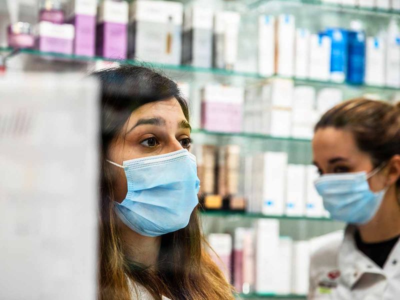Pharmaceutical workers wear face masks to serve customers in a pharmacy in Barcelona, Spain, on Sunday, March 15, 2020. 