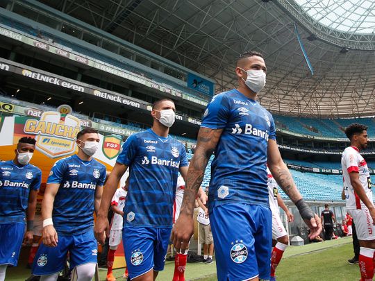 Players of Gremio enter the field wearing protective face masks to prevent the spread of the new Coronavirus, before the match against Sao Luiz