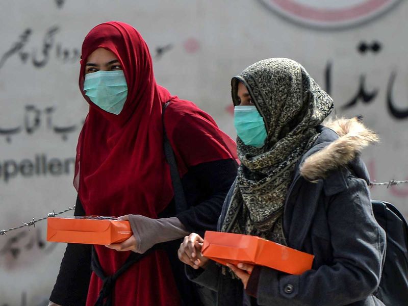 Women wearing facemasks as a preventive measure against the spread of the COVID-19 coronavirus walk along a street in Rawalpindi on March 13, 2020. 