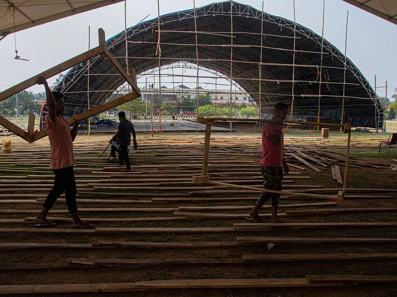 Indian laborers carry wooden frames to make beds to prepare a quarantine center at the Sarusojai sports complex in Gauhati, India.