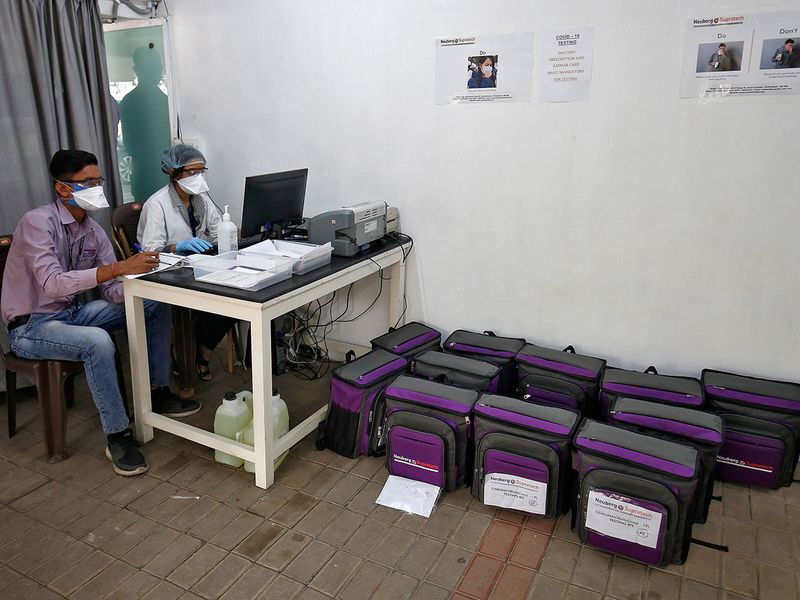 Laboratory technicians sit next to boxes containing coronavirus disease testing kits at a sample collection centre in Ahmedabad.