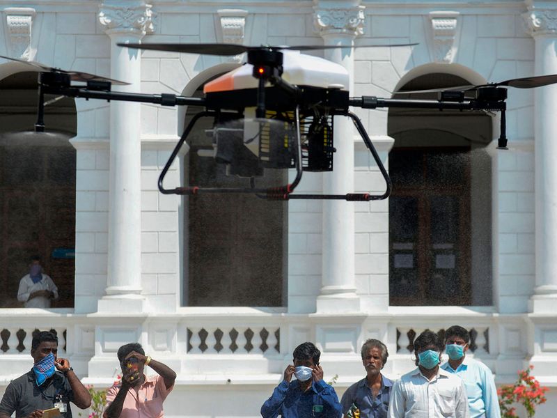 People look at a drone spraying disinfectant at the compound of a municipal office during a government-imposed lockdown as a preventive measure against the COVID-19 coronavirus in Chennai.