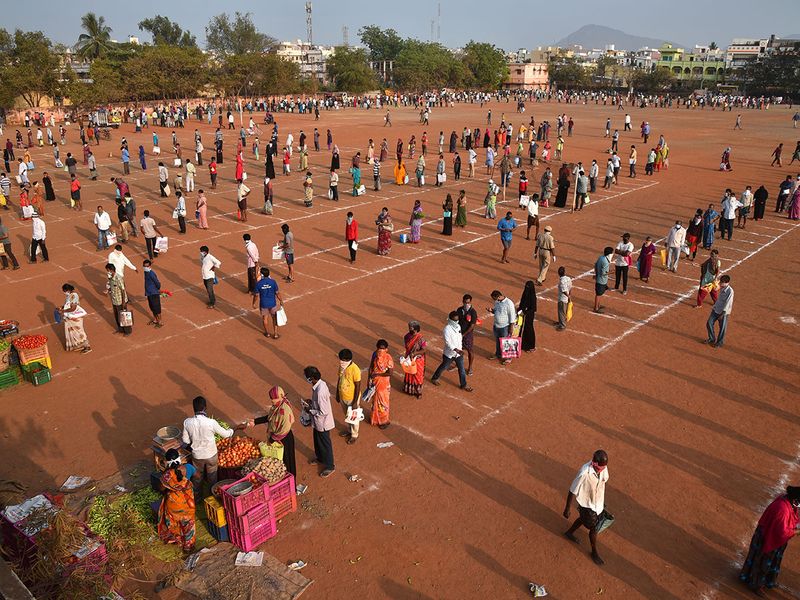 People maintain safe distance as they queue to buy vegetables at a stadium turned into a makeshift market during a 21-day nationwide lockdown to limit the spreading of Coronavirus disease (COVID-19), in Vijayawada in the southern state of Andhra Pradesh.