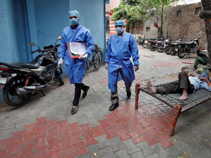 Police officers in protective suits arrive in a residential area to check on people under home quarantine, during a 21-day nationwide lockdown to limit the spreading of coronavirus disease (COVID-19), in Ahmedabad. 