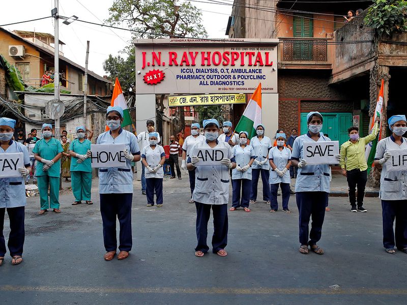 Medical staff members hold placards as they stand outside a hospital to show solidarity with people who are affected by COVID-19 and with doctors, nurses and other healthcare workers from all over the world in Kolkata.