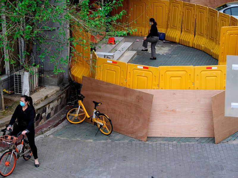 A woman (top) exercises inside a barricaded residential community in Wuhan in China's central Hubei province. 