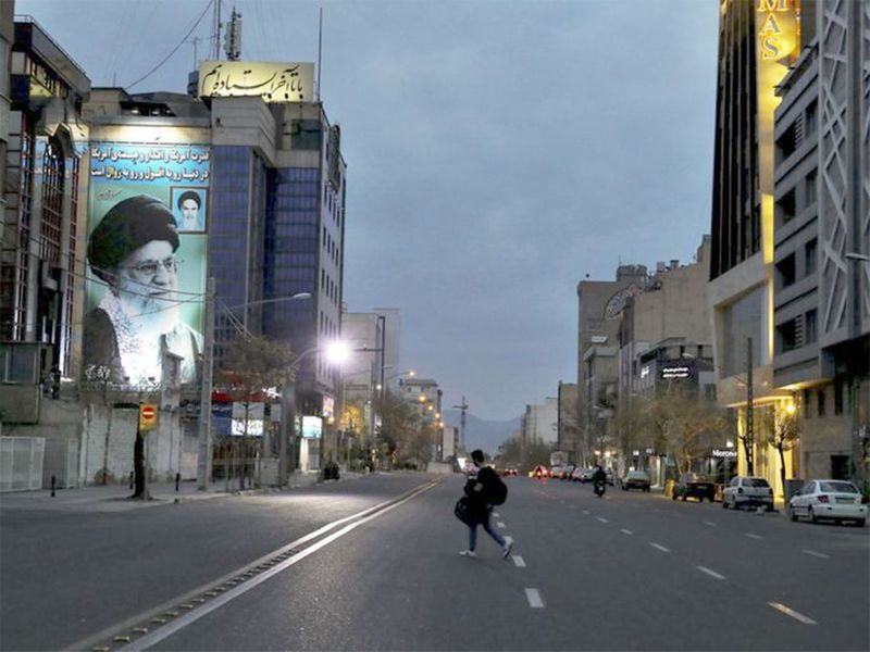 A pedestrian crosses an empty street in Tehran. 