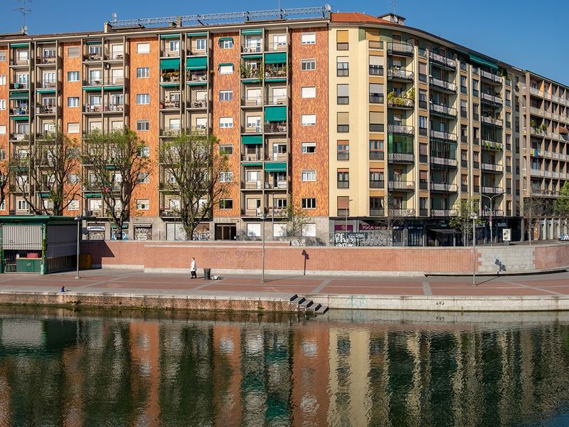 A pedestrian walks on the bank of the Darsena waterway in Milan, Italy.  