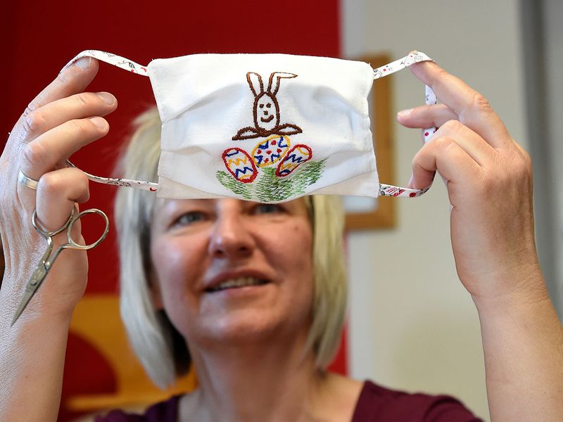 Tailor of traditional costumes Petra Kupke holds a protective mask with Easter motif that she produced in her studio, as the spread of the coronavirus disease continues in Raeckelwitz, Germany.