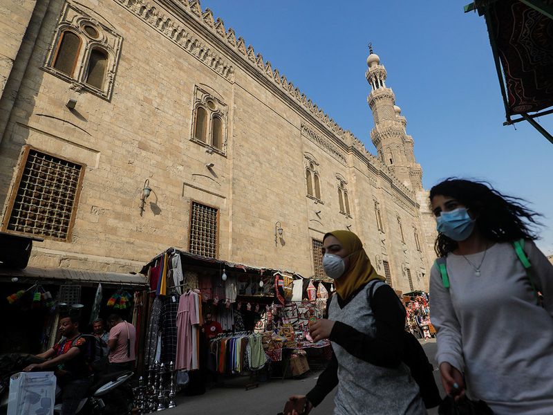 Women wearing protective face masks,  carry traditional Ramadan lanterns, called 