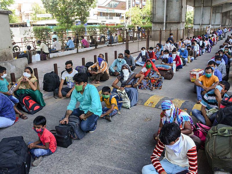 Migrants wait to board city buses