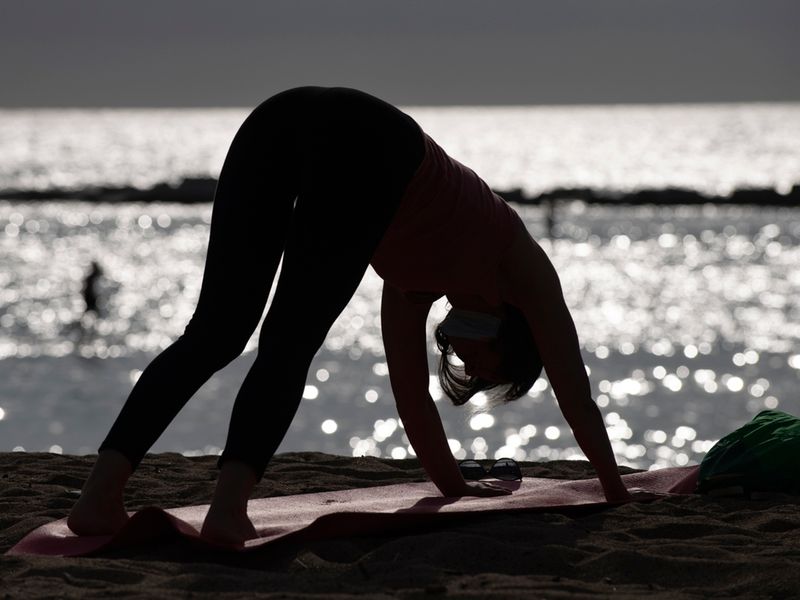 A woman practises yoga at dawn at La Barceloneta Beach in Barcelona.