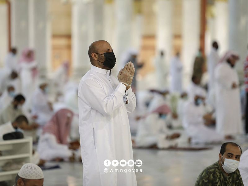 A worshipper in Saudi Arabia wears face mask and gloves