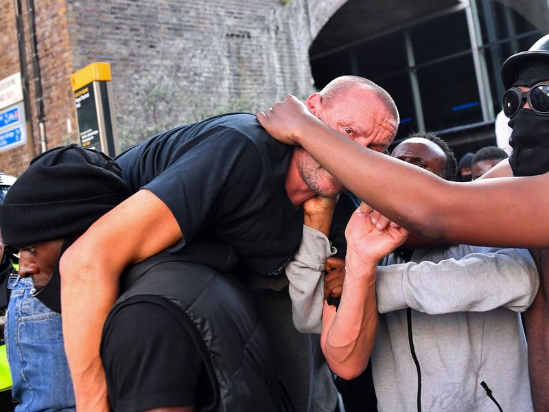 A protester carries an injured counter-protester to safety, near the Waterloo station during a Black Lives Matter protest following the death of George Floyd in Minneapolis police custody, in London, Britain, June 13, 2020. 